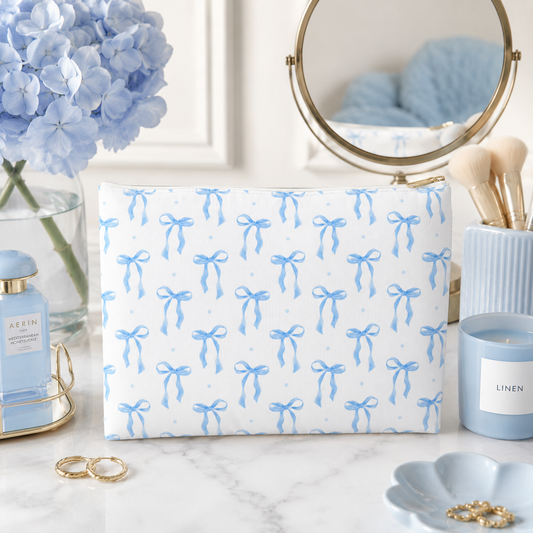 Blue bow makeup bag and cosmetic travel pouch styled on a light blue vanity